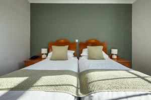 a bedroom with two beds and two night stands with lamps at Stoke Lodge Hotel in Stoke Fleming