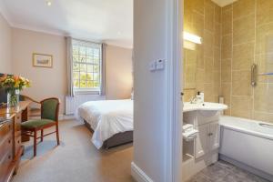 a bedroom with a bed and a sink and a tub at Stoke Lodge Hotel in Stoke Fleming