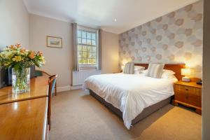 a bedroom with a bed and a desk with a vase of flowers at Stoke Lodge Hotel in Stoke Fleming
