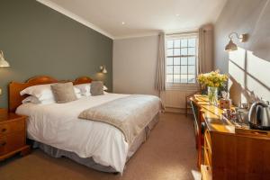 a bedroom with a bed with white sheets and a window at Stoke Lodge Hotel in Stoke Fleming