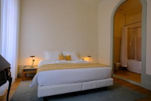 ein Schlafzimmer mit einem großen weißen Bett und einem Tisch in der Unterkunft Cravo’s Heritage House in Pinhel