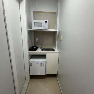 a small kitchen with a sink and a microwave at Loft Lux SM 06 (Smart TV, Ar condicionado, Cozinha) in Chapecó