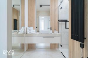 een badkamer met een wastafel en een spiegel bij Zielona 16 D&D Apartments in Międzywodzie +32 foto's