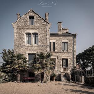 une ancienne maison en pierre avec deux palmiers devant elle dans l'établissement Maison d'Hôtes La Guérandière, à Guérande