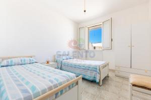 une chambre avec deux lits et une fenêtre dans l'établissement Salento and more - Appartamento Grecale Piano Terra, à Torre Pali