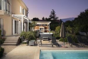 a house with a pool and chairs and an umbrella at Villa BELLA - beautiful and modern house with pool, souna, jacuzzi & playground, Ližnjan - Istra in Ližnjan