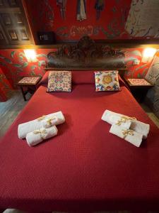 Una cama roja con tres toallas blancas. en Catania Sicula Folk, en Catania