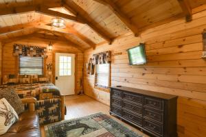 Dormitorio en cabaña de madera con cama y TV en 1 Mi to Current River Cozy Studio Cabin!, en Van Buren