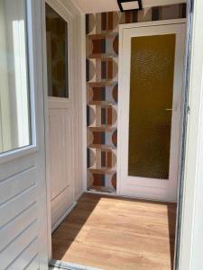 a hallway with a door and a wall with a window at Relax Chalet with hottub in Voorthuizen +12 photos