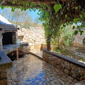 eine Steinmauer mit einer Bank und einem Steinkamin in der Unterkunft Hello Sunshine in Veli Iž