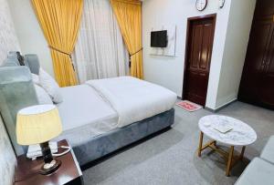 a bedroom with a bed and a table with a lamp at Hotel The Shalimar in Lahore