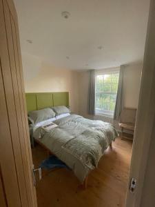 a bedroom with a bed with a green headboard and a window at Cottage of Content in Wivenhoe