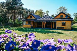 a house with purple flowers in front of it at Wczasy u Juliana in Drewnica