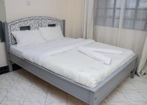 a bed with white sheets and pillows on it at Nanyuki Modern 1 Bedroom in Nanyuki