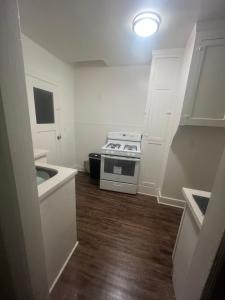 Una pequeña cocina con estufa y gabinetes blancos. en Living downtown, en Long Beach