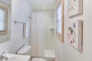 a white bathroom with a shower and a toilet at Walk to Shops and Dining Cozy Osterville Cottage in Osterville +17 photos