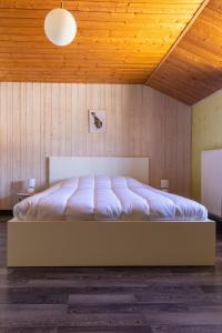 un grand lit dans une chambre avec un plafond en bois dans l'établissement Domaine Chez Feldus, à Villers-Farlay