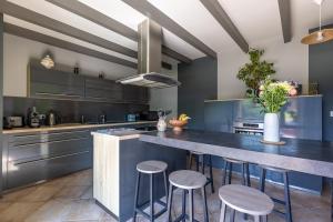 une cuisine avec des placards bleus et un grand îlot avec des tabourets dans l'établissement Domaine Chez Feldus, à Villers-Farlay