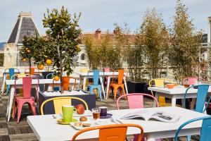 eine Gruppe von Tischen und Stühlen auf einer Terrasse in der Unterkunft Ibis Styles Hyères Rooftop & Spa in Hyères