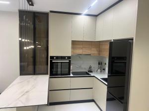 a kitchen with white cabinets and black appliances at Sunrise Home Getaway - Shëngjin in Shëngjin