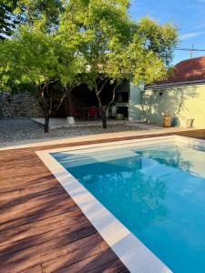 a swimming pool with a wooden deck next to a house at Almond Buna PoolHouse in Mostar