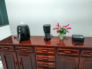 a wooden dresser with two coffee makers and flowers on it at Residencial Alves in Paragominas