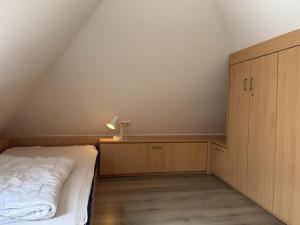 an attic bedroom with a bed and a cabinet at Doppelhaushälfte in Neßmersiel in Neßmersiel