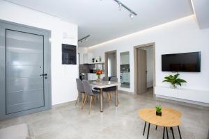 a living room with a table and chairs and a tv at RENI APARTMENT Faliraki in Faliraki