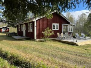 a small red house with a deck and chairs on it at Hus Björklund in Hällefors