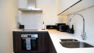 a kitchen with a sink and a stove at Manchester City Centre Apt, with Free Secured Parking & Balcony, Sleeps 4 - FREE 1 HOUR EARLY CHECK IN FOR 2 NIGHT STAYS ONLY UNTIL THE END OF MAY in Manchester +32 photos