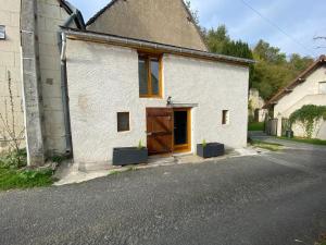 a white house with a brown door and two plants at La Tiny Blue - maison insolite pour 2 - sans Tv in Saint-Aignan