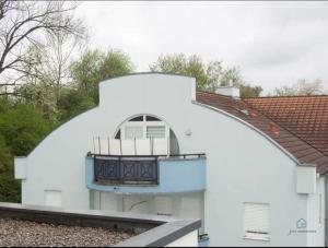 a white house with a round window and a balcony at Bright attic apartment near Augsburg in Gersthofen