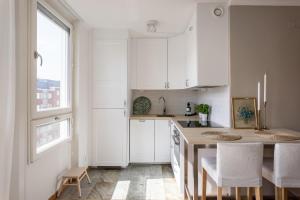 a kitchen with white cabinets and a table and chairs at Stylish Studio Apartment - Center in Stockholm