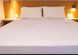 a bed with white sheets and pillows in a room at Resort Premium Salinas in Salinópolis +9 photos