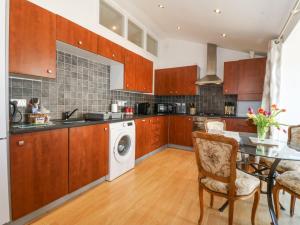 a kitchen with a table and a washing machine at Maritime Mews, 6 The Oakleys in Porthmadog