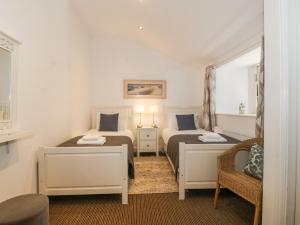 a bedroom with two beds and a chair at Maritime Mews, 6 The Oakleys in Porthmadog