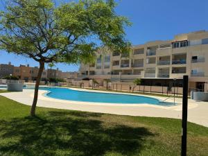 a tree in front of a building with a swimming pool at Sunset Beach Front in Almerimar