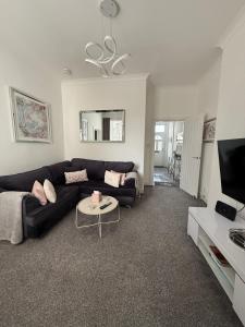 a living room with a black couch and a tv at Cosy Cottage in Stirling