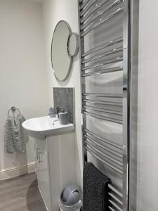 a white bathroom with a sink and a mirror at Cosy Cottage in Stirling +11 photos