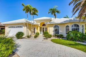 a yellow house with palm trees in front of it at Pool, Spa and Dock Waterfront Tarpon Point Home in Cape Coral