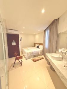 a bathroom with a bed and a sink and a tub at Vila do Morro Pousada in Morro de São Paulo