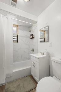 a white bathroom with a tub and a toilet and a sink at Fun Family getaway - NYC & NWK w free parking in Newark