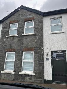 ein Backsteinhaus mit grüner Tür und Fenstern in der Unterkunft Tildara Terrace in Portstewart