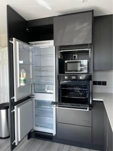 eine Küche mit einem offenen Kühlschrank und einer Mikrowelle in der Unterkunft Tildara Terrace in Portstewart