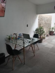 a glass table with two chairs and a laptop on it at Casa Naty in Mexico City