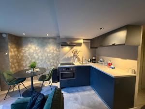 a kitchen with blue cabinets and a table with chairs at Katwijks geluk in Katwijk aan Zee