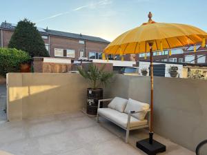a chair and an umbrella on a patio at Katwijks geluk in Katwijk aan Zee