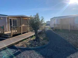 a cabin with a wooden walkway next to a tree at Camping 3 étoiles - Parc aquatique - ccaehgc in Déols