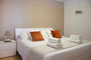 a bedroom with a white bed with orange and white pillows at Perla d'Orlando in Capo dʼOrlando