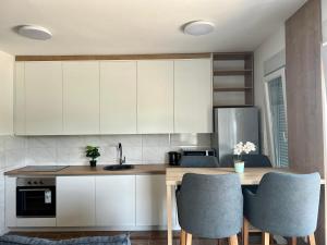 a kitchen with white cabinets and a table with chairs at Prima in Bosanska Dubica